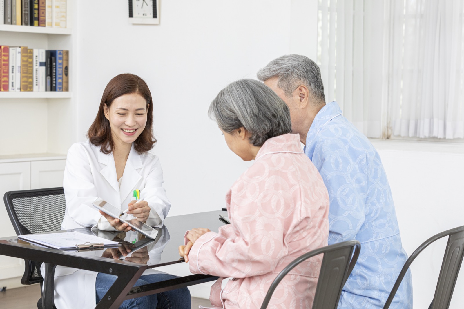 의료진이 노년 부부에게 태블릿 화면을 보여주며 진료비와 서류에 대해 설명하는 모습
